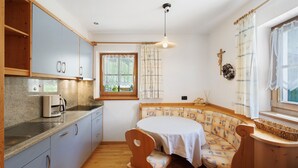 Una cocina compacta con comedor, armarios de madera, cafetera y ventana con cortinas.