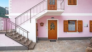 Un edificio rosa con puerta de madera, un balcón y una escalera de piedra.