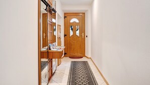 Un pasillo con una puerta de madera, un escritorio con papeles y una alfombra estampada.