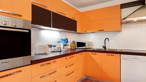 Una cocina con armarios color naranja, un horno Bosch, un microondas y un lavavajillas.