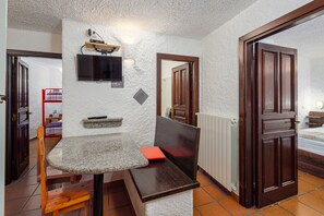 Une pièce avec un banc en pierre, un téléviseur fixé au mur, une porte en bois et un radiateur.