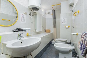 Une salle de bain comprenant un grand lavabo, des toilettes, un bidet et une douche avec un rideau.