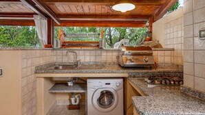 A compact kitchen with a washing machine, a sink, and a gas stove.