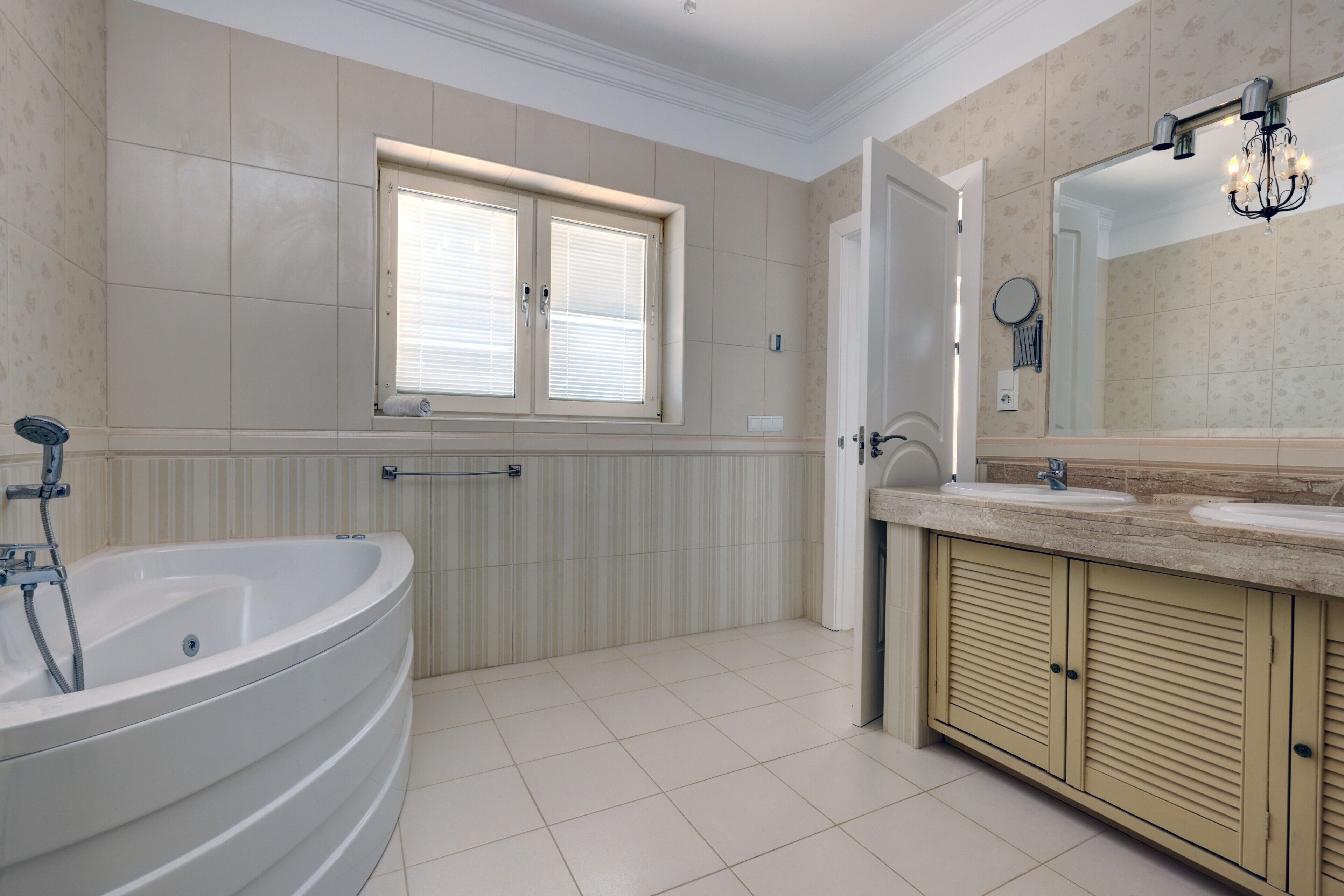 Un baño con bañera, lavamanos, espejo y ventana.