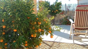 A patio area with a wooden chair, a small tree with oranges, and a fence in the background. - Villa Miantojo near the coast with Private Pool, Terrace, A/C & Wi-Fi. (Mazarrón)