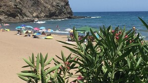 A beach with umbrellas and people, a rocky cliff, and a clear sky. - Villa Miantojo near the coast with Private Pool, Terrace, A/C & Wi-Fi. (Mazarrón)