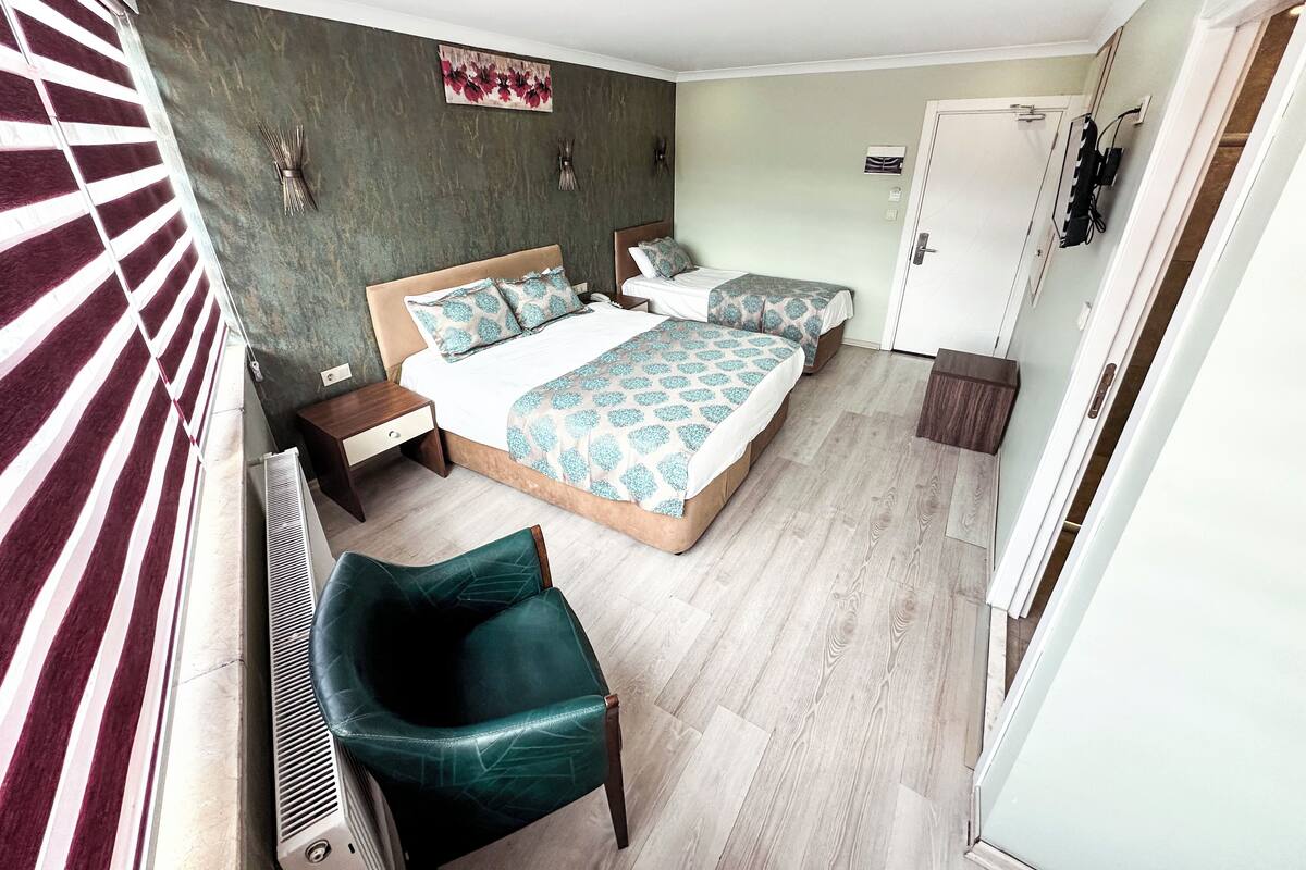 A bedroom with a bed, two bedside tables, a chair, a radiator, and a wardrobe.
