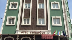 Um edifício de vários andares com fachada verde e detalhes brancos, apresentando uma placa com a inscrição "OTEL SAGIROGLU" na entrada.