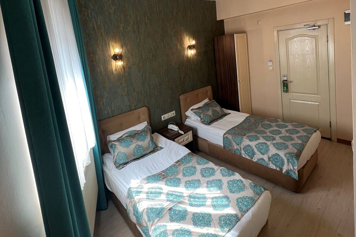 A hotel room with two beds, a wardrobe, and a door.