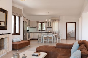 Un vaste espace de vie doté d’une cheminée, d’une table à manger avec des chaises et d’une cuisine située au fond de la pièce.