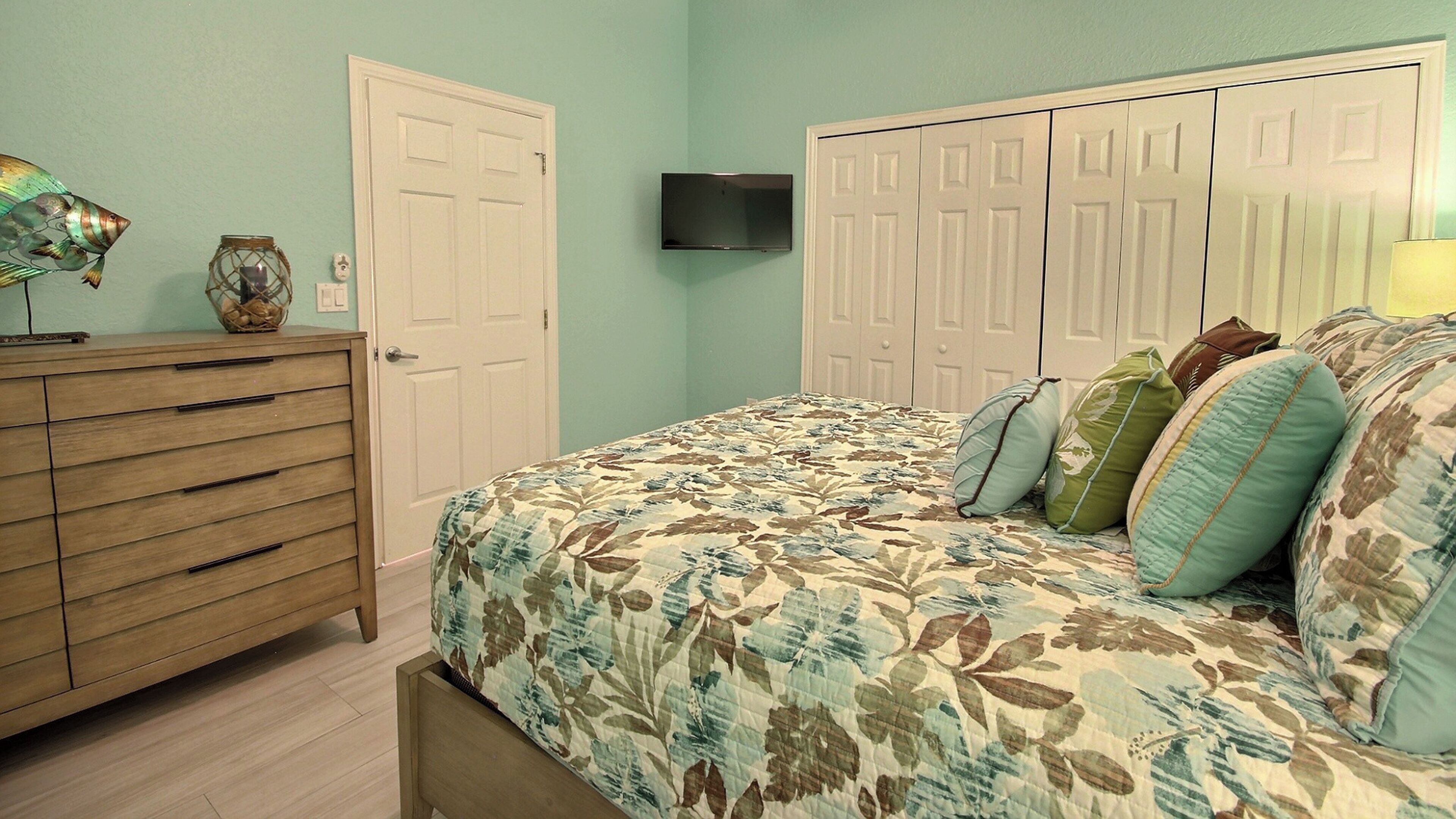 Une chambre à coucher comprenant un lit, une commode, une armoire et un téléviseur à écran plat.