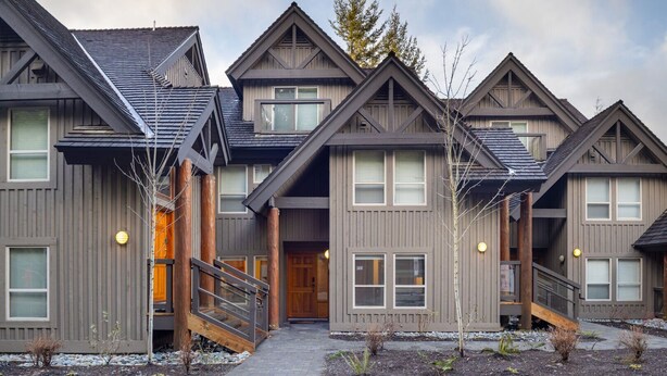 A row of modern, multi-story buildings with a uniform architectural style, featuring large windows and a central entrance. - 2BR | Painted Cliff | Ski in/out | Communal Hot Tub | Wood Burning Fireplace | Free Parking (Whistler)