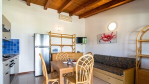 Une cuisine compacte avec un coin repas, un banc intégré et un téléviseur fixé au mur.