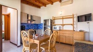 Une cuisine de taille réduite comprenant une table à manger, des chaises et un téléviseur fixé au mur.