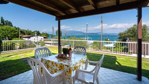 Une terrasse extérieure avec une table dressée pour deux personnes, offrant une vue panoramique sur la mer et les montagnes.