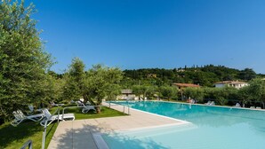 Une piscine dotée de chaises longues et offrant une vue dégagée sur une colline parsemée de bâtiments.