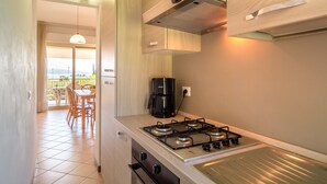 A compact kitchen with a gas stove, a coffee maker, and a view to an outdoor balcony. - Mansion by Lake Garda with Pools & Olive Trees (Manerba del Garda)