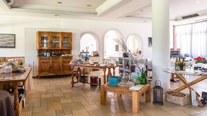 A spacious living area with a wooden dining table, a kitchen with wooden cabinets, and a glass coffee table. - Apartment in Salò with Pool & Olive Groves (Cunettone)