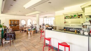 A spacious kitchen with a bar area, wooden cabinets, and red bar stools. - Apartment in Salò with Pool and Olive Groves (Cunettone)