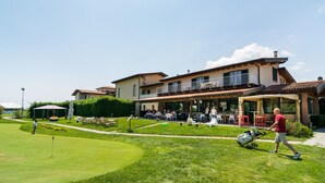 A golf course with a clubhouse, outdoor seating, and a well-maintained lawn. - Modern Salo Flat with Pool (Cunettone)