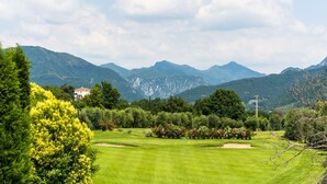 A golf course with a house in the background and mountains in the distance. - Modern Salo Flat with Pool (Cunettone)