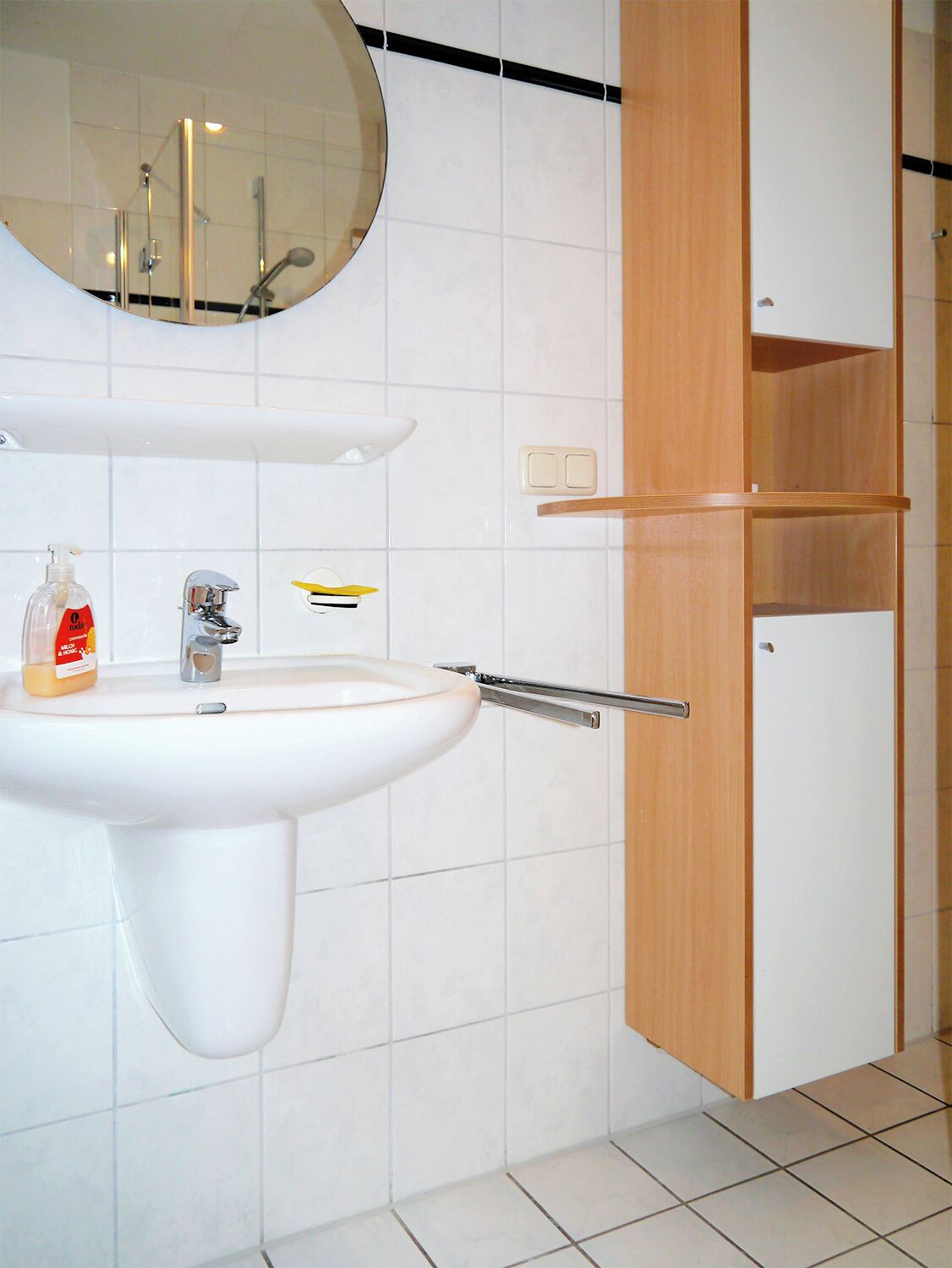 Une salle de bain avec un lavabo blanc, un miroir et un meuble en bois.