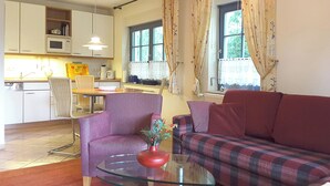 Un espace de vie compact comprenant un canapé, une table basse en verre et un coin repas avec une chaise et une table.