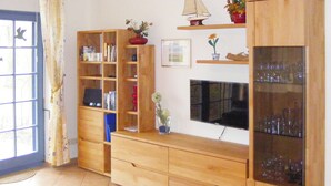 Un salon avec un meuble TV en bois, des étagères et une vitrine.