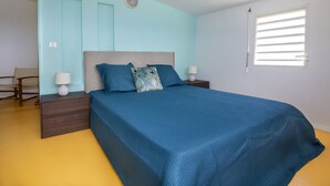 A bedroom with a large bed, two nightstands, a chair, and a window with blinds.
