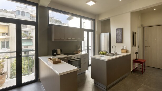 Een moderne keuken met een centraal eiland, een inbouwoven en een groot raam met uitzicht op de stad.