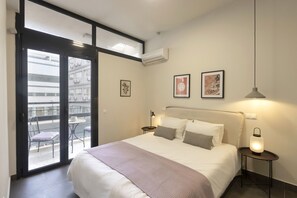 Une chambre à coucher avec un lit, un balcon avec des chaises et une table de chevet avec une lampe.
