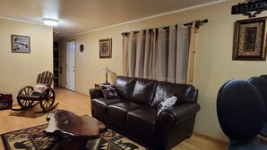 A living room with a leather sofa, a rocking chair, a coffee table, and a television.
