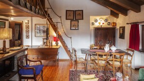 Un'area pranzo rustica con mobili in legno, una scala e una collezione di stoviglie appese al muro.