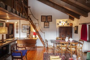Ein rustikaler Essbereich mit Holzmöbeln, einer Treppe und einer Sammlung von Geschirr an der Wand.