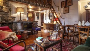 Un accogliente soggiorno con camino, arredamento in legno e una scala che conduce a un piano superiore.