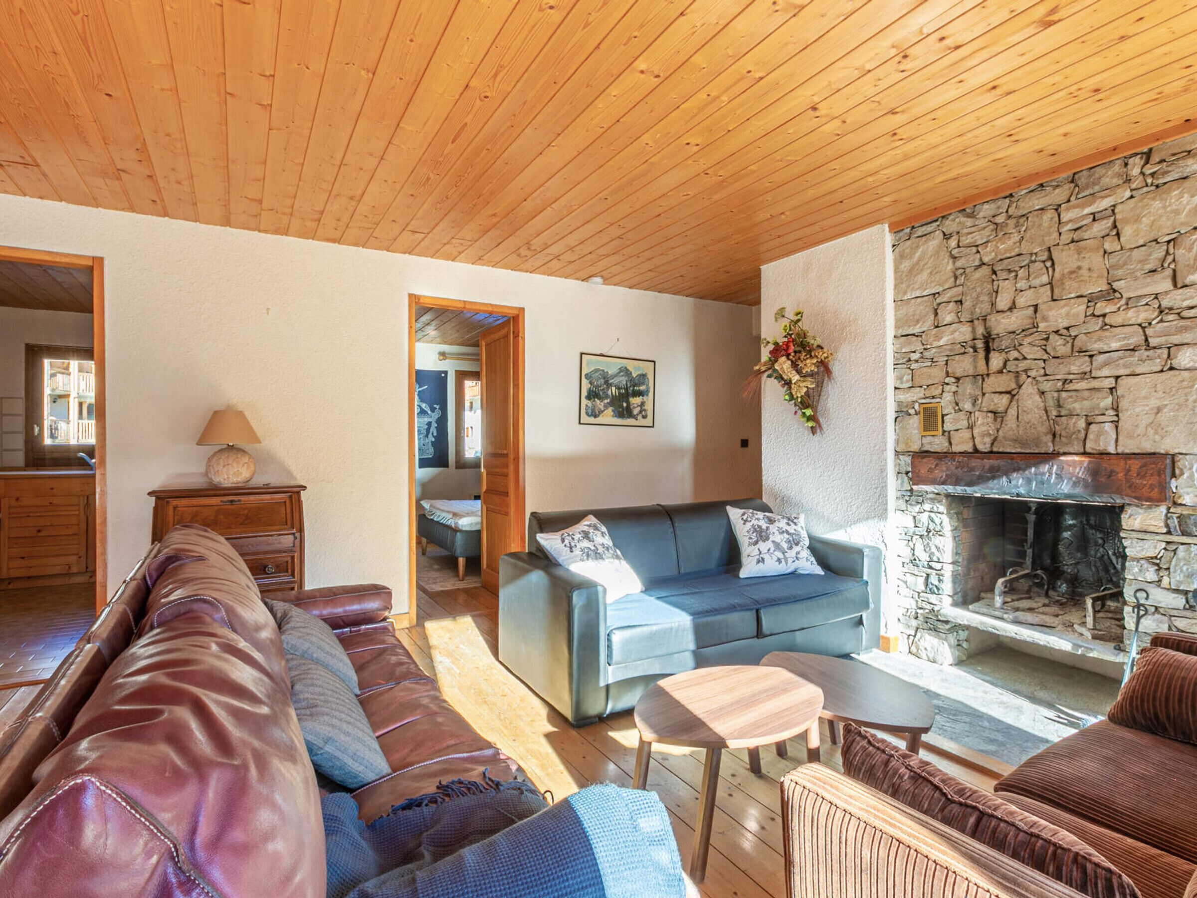 Una sala acogedora con chimenea de piedra, un sofá y techo de madera.