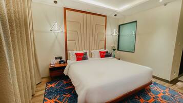 A hotel room with a large bed, a nightstand, a lamp, and a mirror.