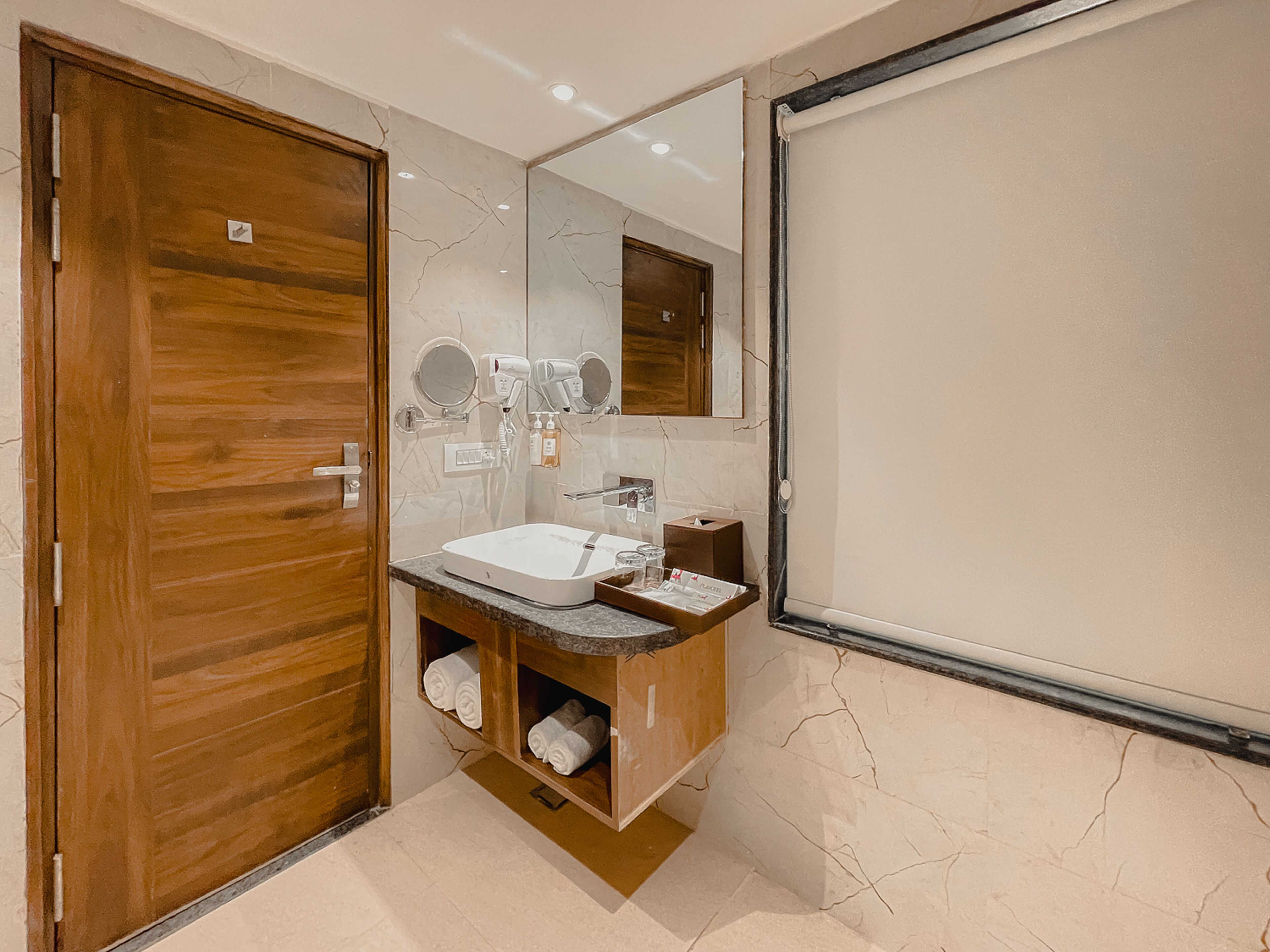 Un baño moderno con puerta de madera, un lavabo blanco, un espejo y un perchero para toallas.