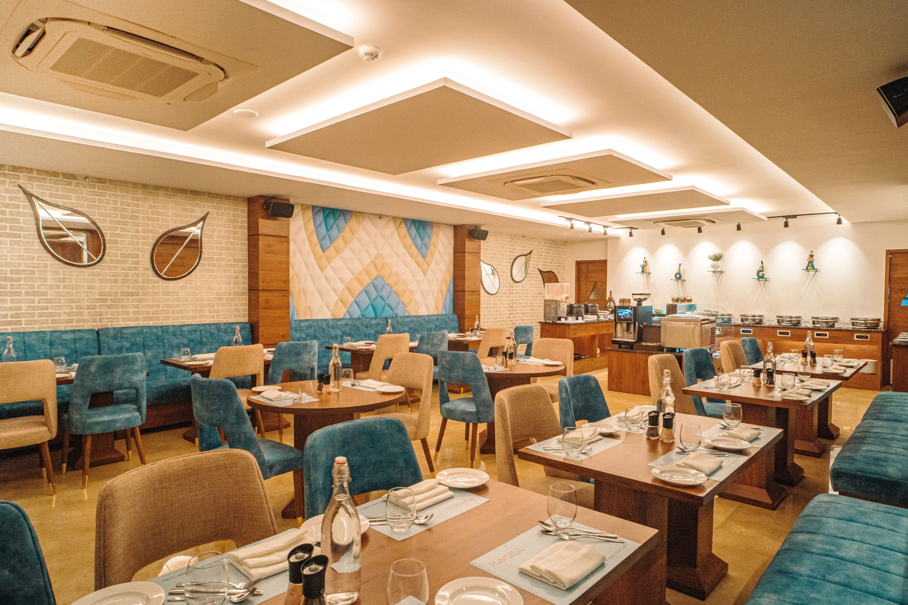 A restaurant with booths and tables, a kitchen in the background, and decorative wall mirrors.