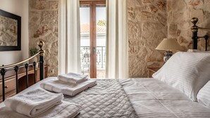 Ein Schlafzimmer mit Steinwand, einem Bett mit gesteppter Bettdecke, einem Nachttisch mit Lampe und einem Fenster mit Vorhängen.