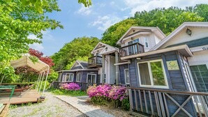 Une rangée de cabanes en bois dotées de balcons, entourées d’une végétation luxuriante et de plantes en fleurs.
