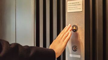 Una mano presionando un botón en el panel de control de un ascensor, con un sistema de seguridad y un lector de tarjetas.