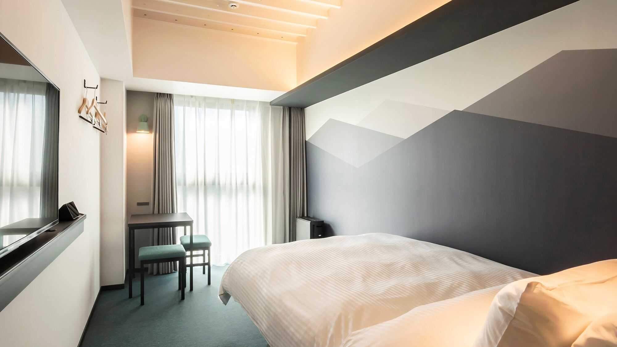 A hotel room with a bed, a desk, and a chair.