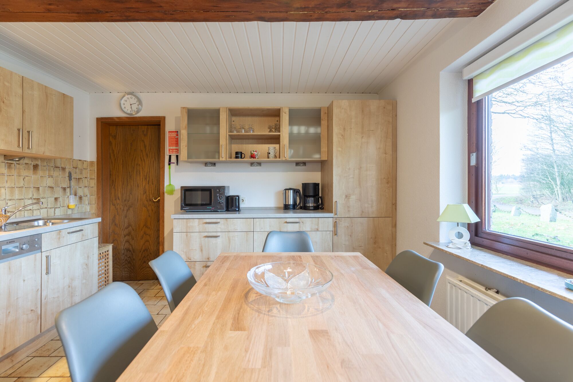 Cocina compacta con armarios de madera, microondas y cafetera.