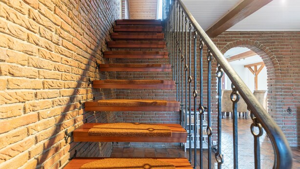 A staircase with wooden steps and metal railings in a building with brick walls. - Vacation home de Maade for up to 6 people (Enge-Sande)