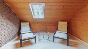 A small, sloped-roofed room with two chairs and a glass table, a brick wall, and a wooden ceiling. - Vacation home de Maade for up to 6 people (Enge-Sande)