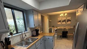 A modern kitchen with grey cabinets, a stainless steel sink, and a marble floor. - Beautifully design house for relaxation (Warner Robins)
