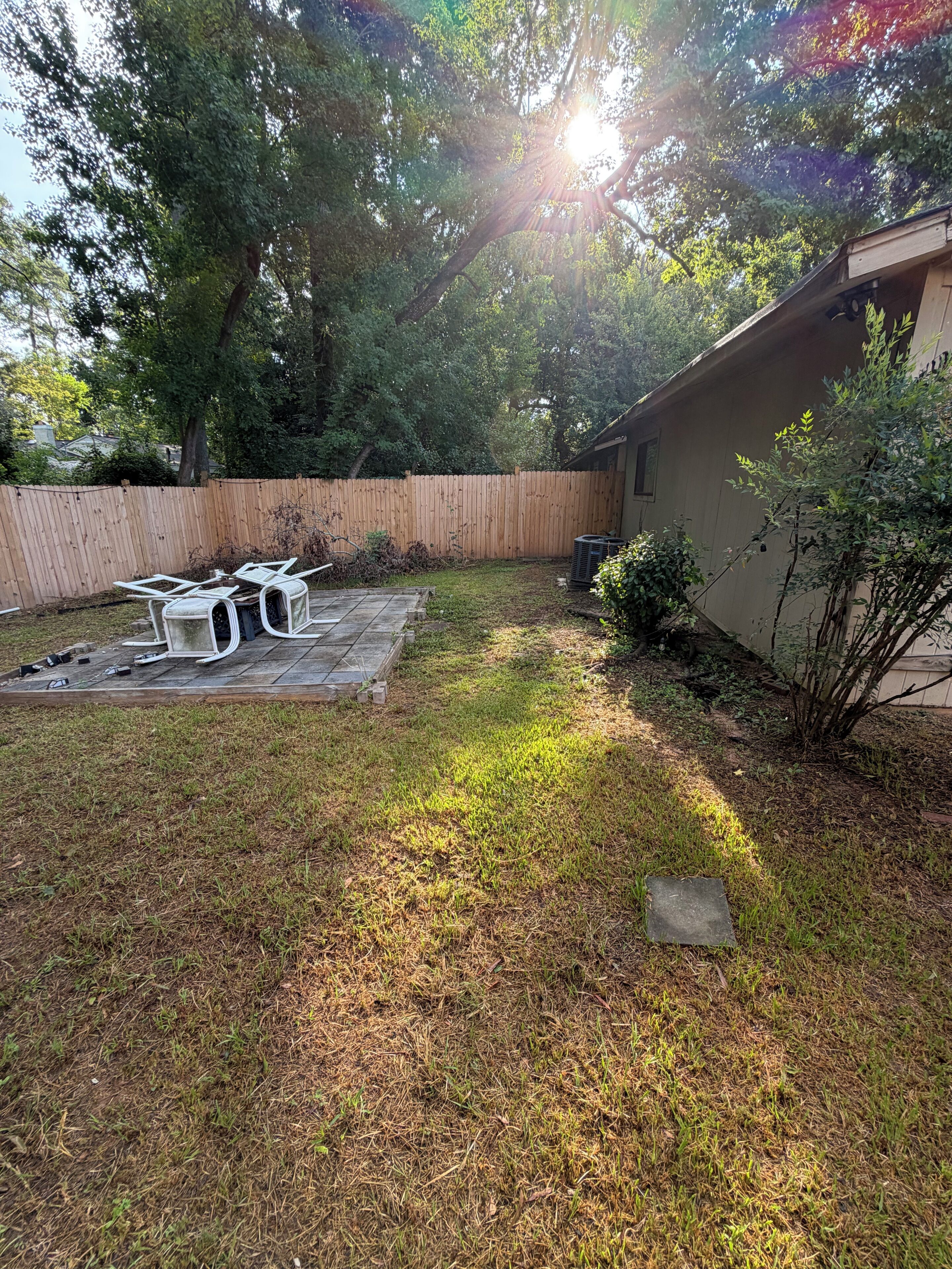 A backyard with a wooden deck, a small table, and a chair.