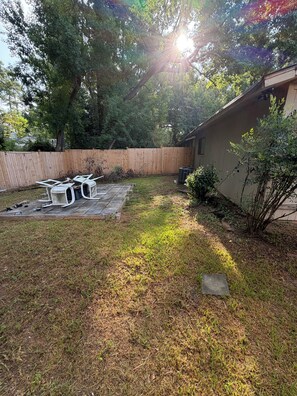 A backyard with a wooden deck, a small table, and a chair.