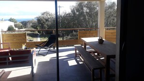 A balcony with a wooden table, a bench, and a chair. - Superb villa, 5km from Solenzara. Air-conditioning, swimming pool, fenced grounds. (SOLARO)